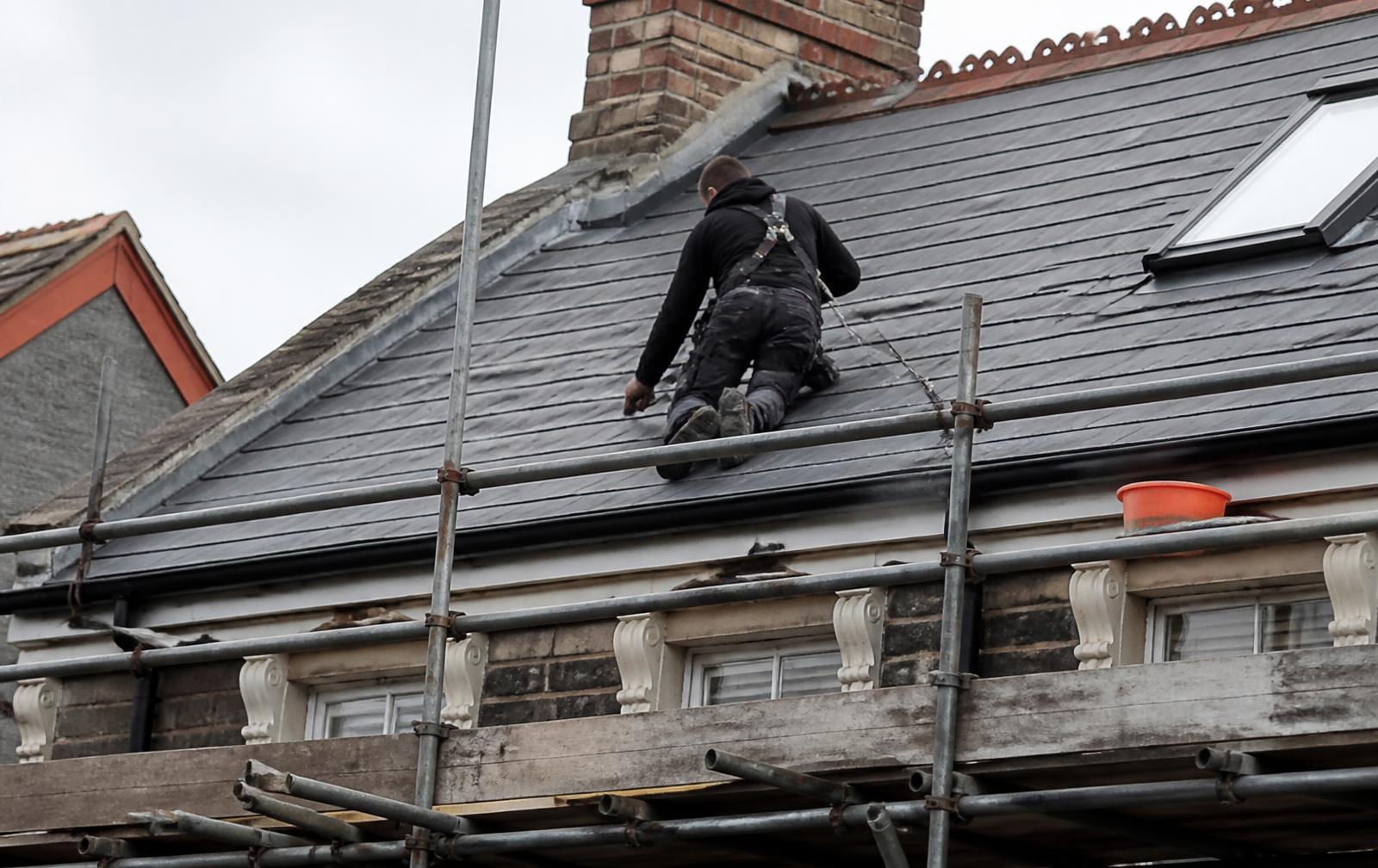 Roofer repairing a slate roof on a UK home